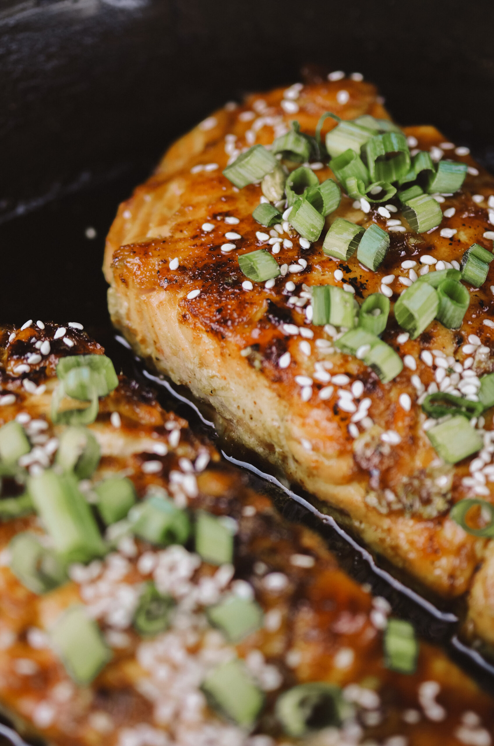 Two maple-glazed salmon fillets in cast iron skillet