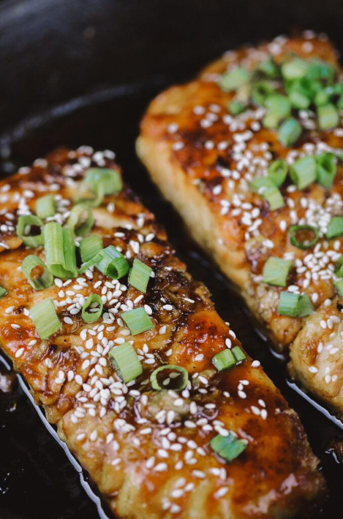 Two maple-glazed salmon fillets in cast iron skillet